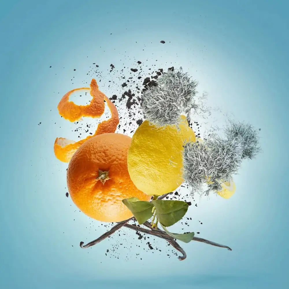 An artistic composition of oranges, a lemon, vanilla pods, and dark particles floating against a blue background.