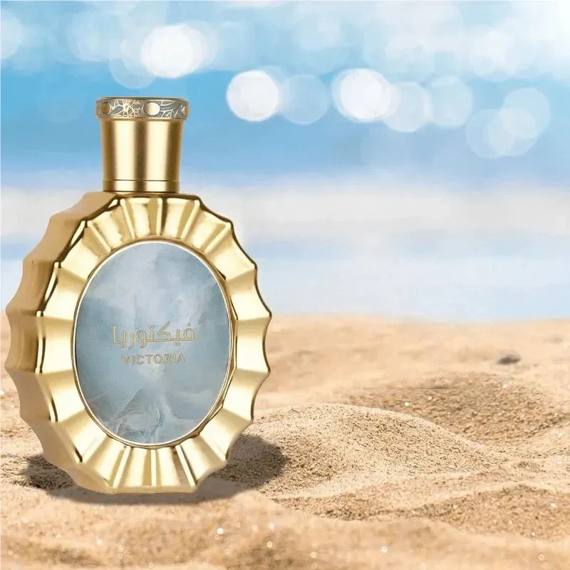 Golden perfume bottle with blue center on a sandy beach background.