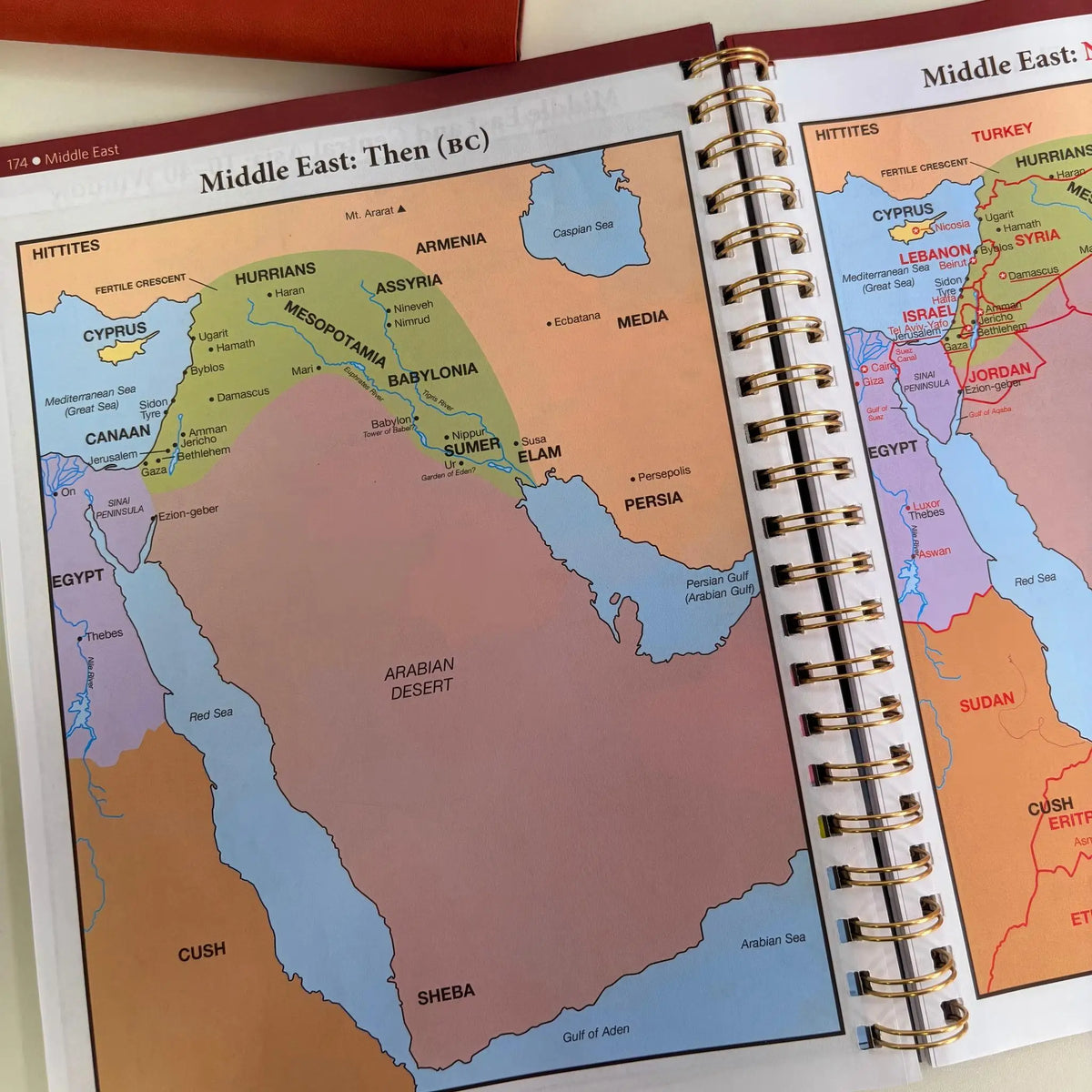 An open spiral-bound Bible study book showing ancient Middle East maps.