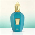 A turquoise glass perfume bottle with a gold stopper, standing on a white surface against a light gradient background.