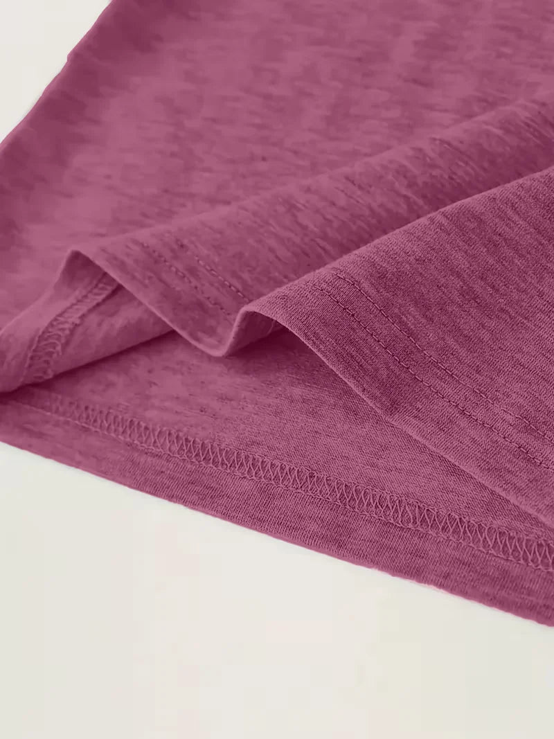 Close-up of the hem of a plain maroon t-shirt fabric