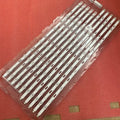 Set of TV LED backlight strips in clear plastic packaging on a red textured surface.