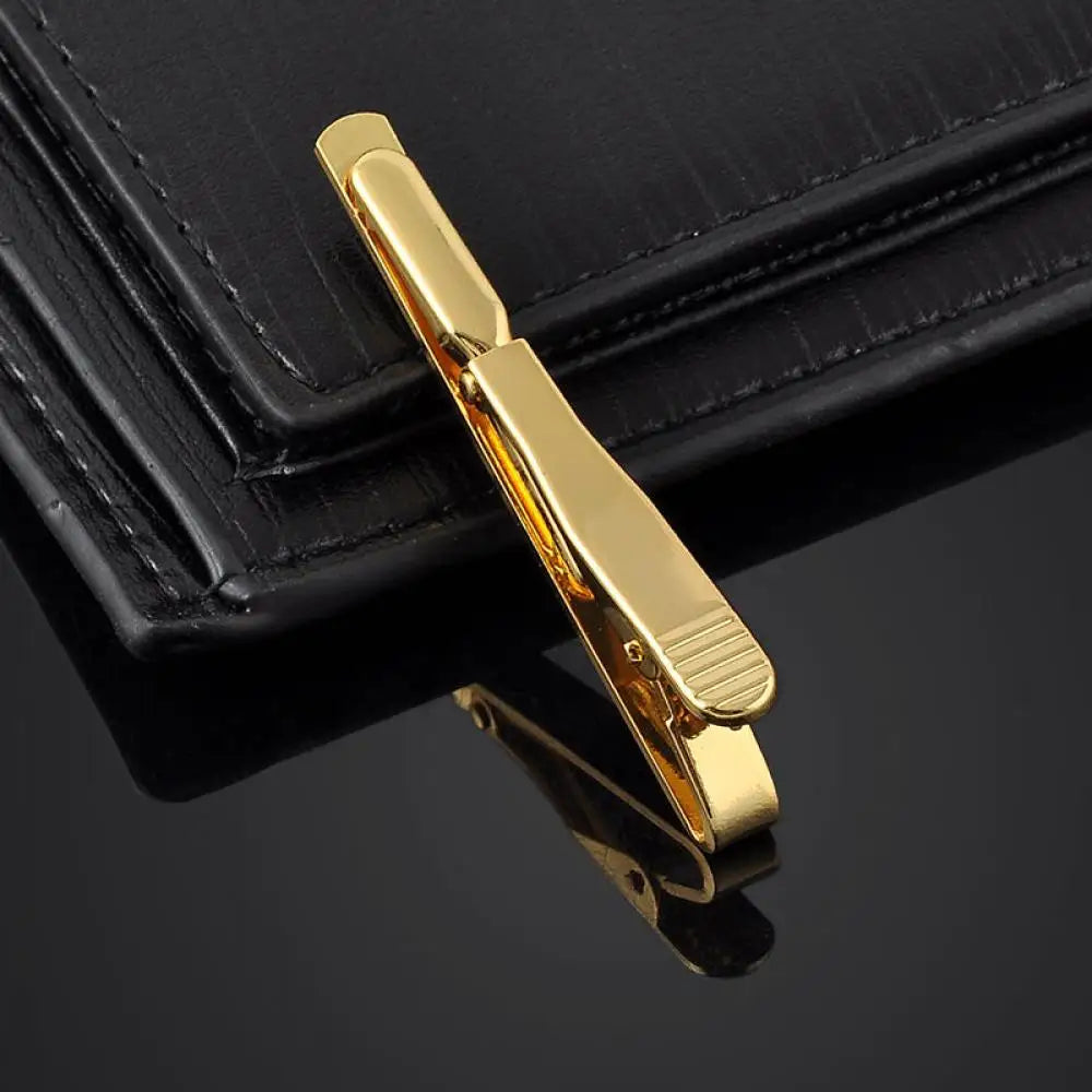 Gold tie bar on a black surface