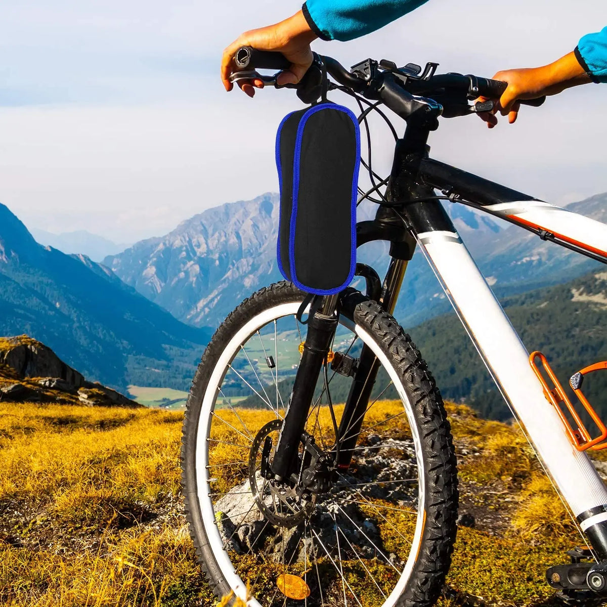 A folded camping chair in a carry bag attached to the handlebars of a mountain bike.