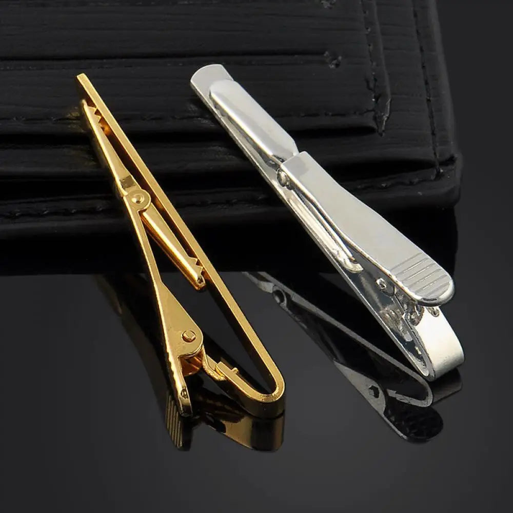 Gold and silver metal tie bars on a black surface