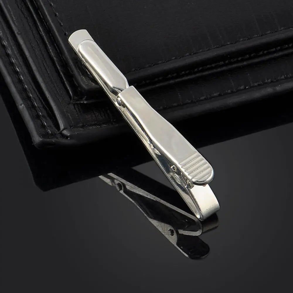 Silver tie bar on a black surface