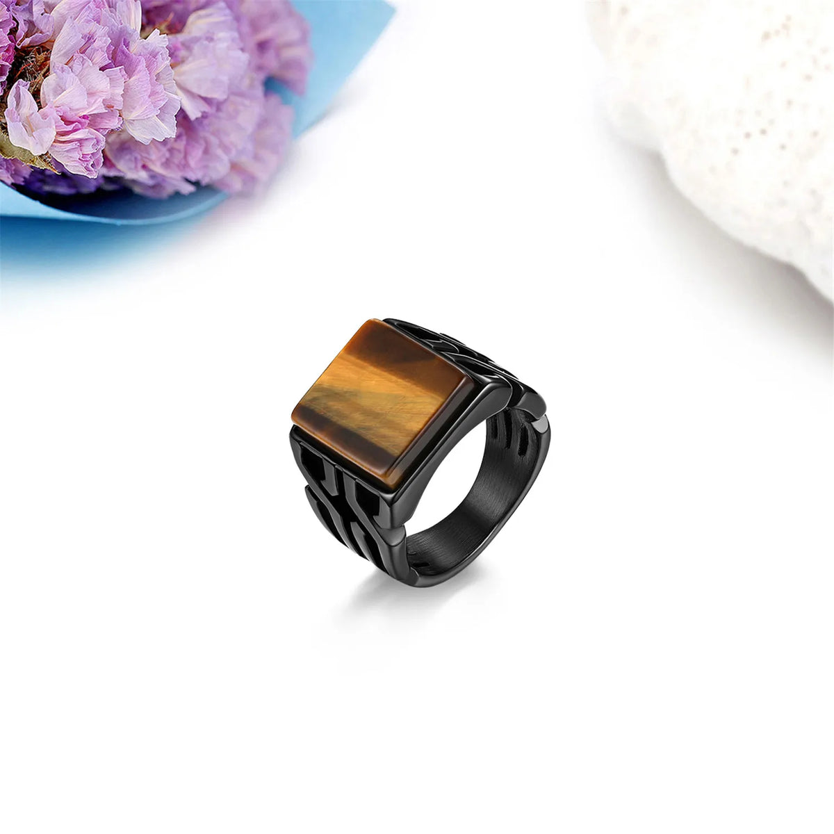 Men's square signet ring with a tiger eye gemstone on a white background with decorative flowers