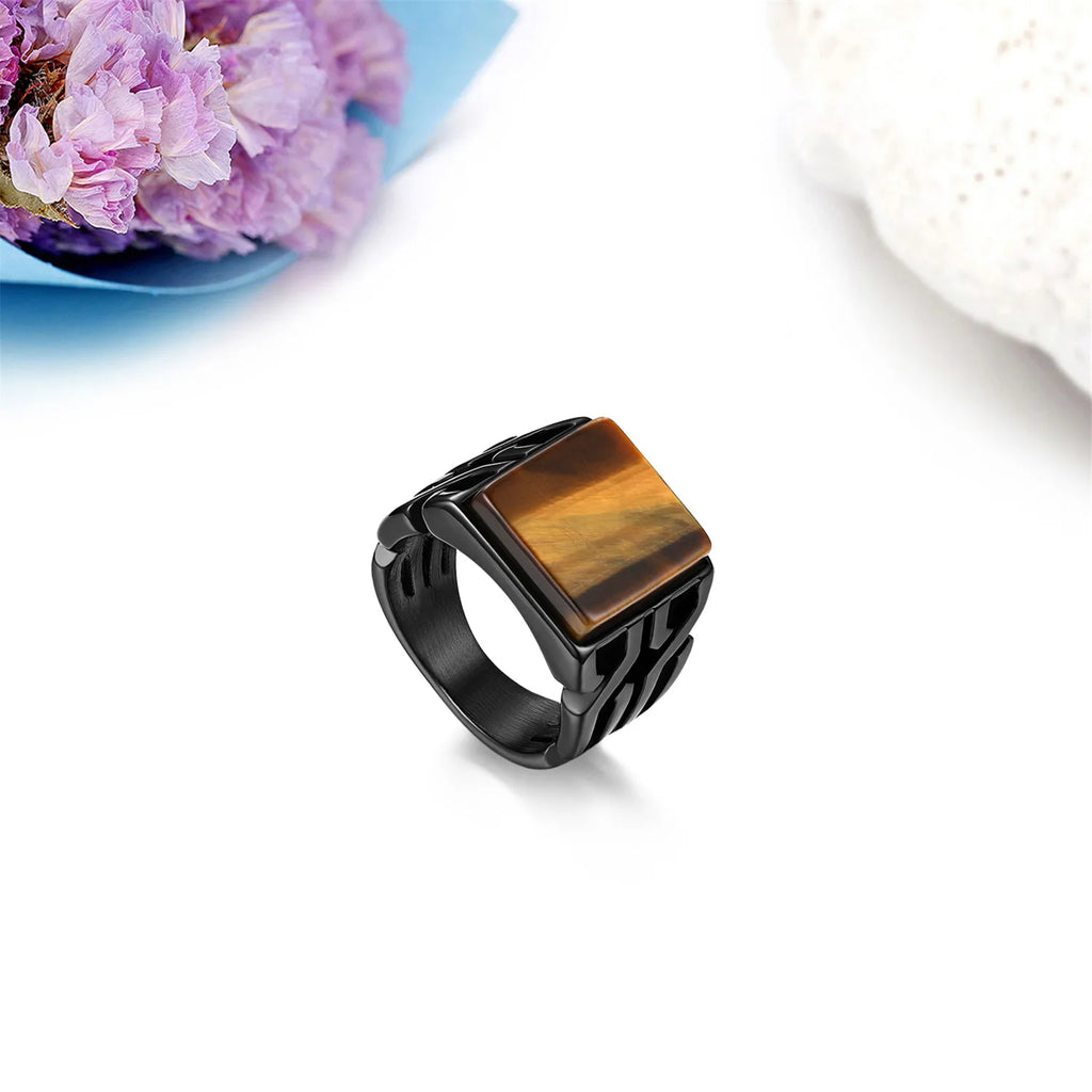 Men's square signet ring with a tiger eye gemstone on a white background with decorative flowers