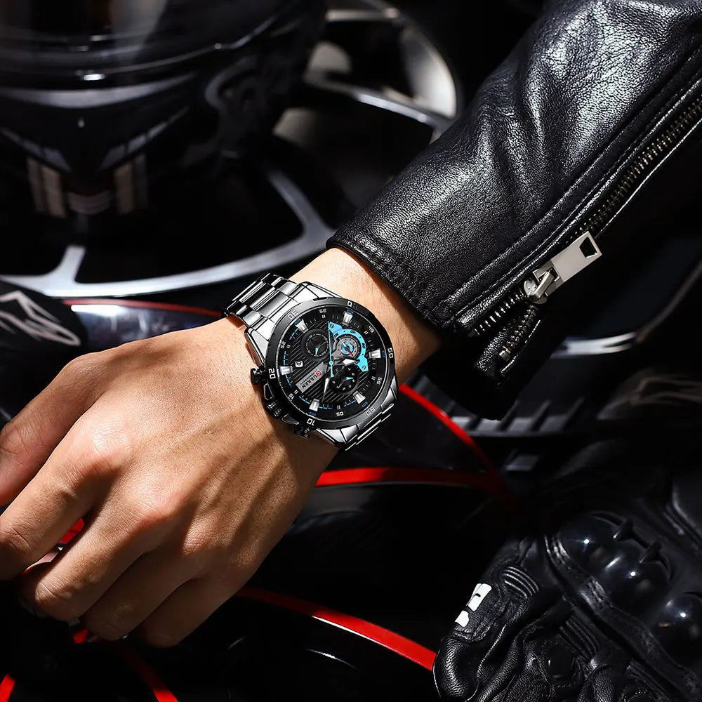 Silver stainless steel chronograph watch worn on a wrist in a leather jacket.