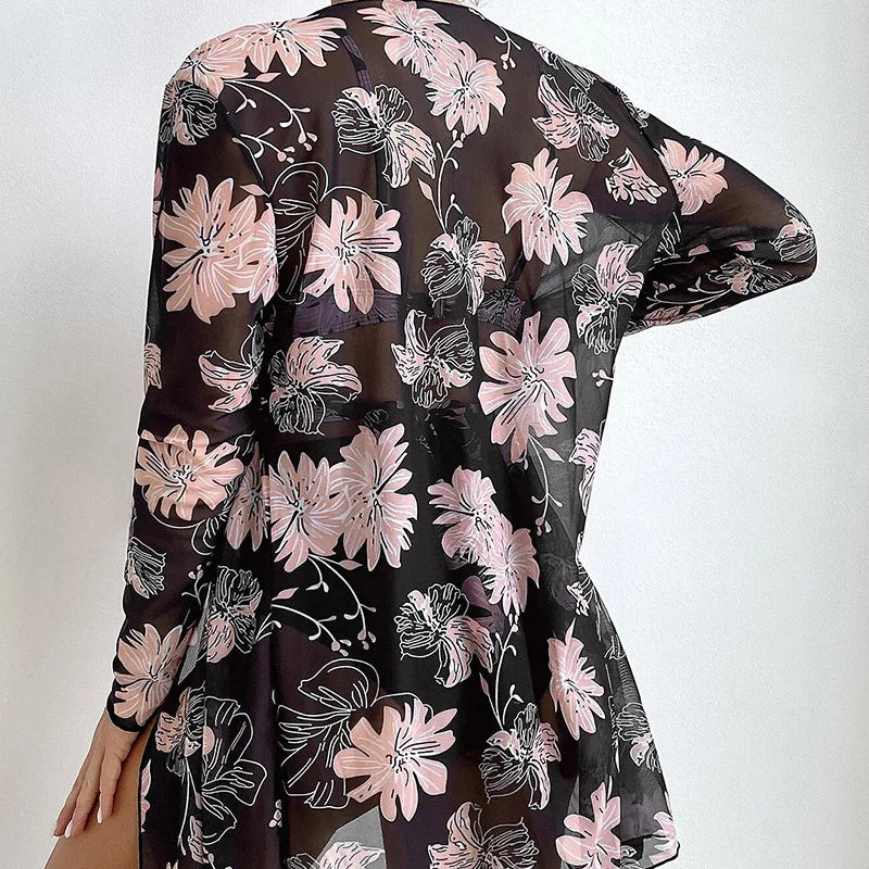 Back view of a person wearing a sheer black and pink floral long-sleeve cover-up.