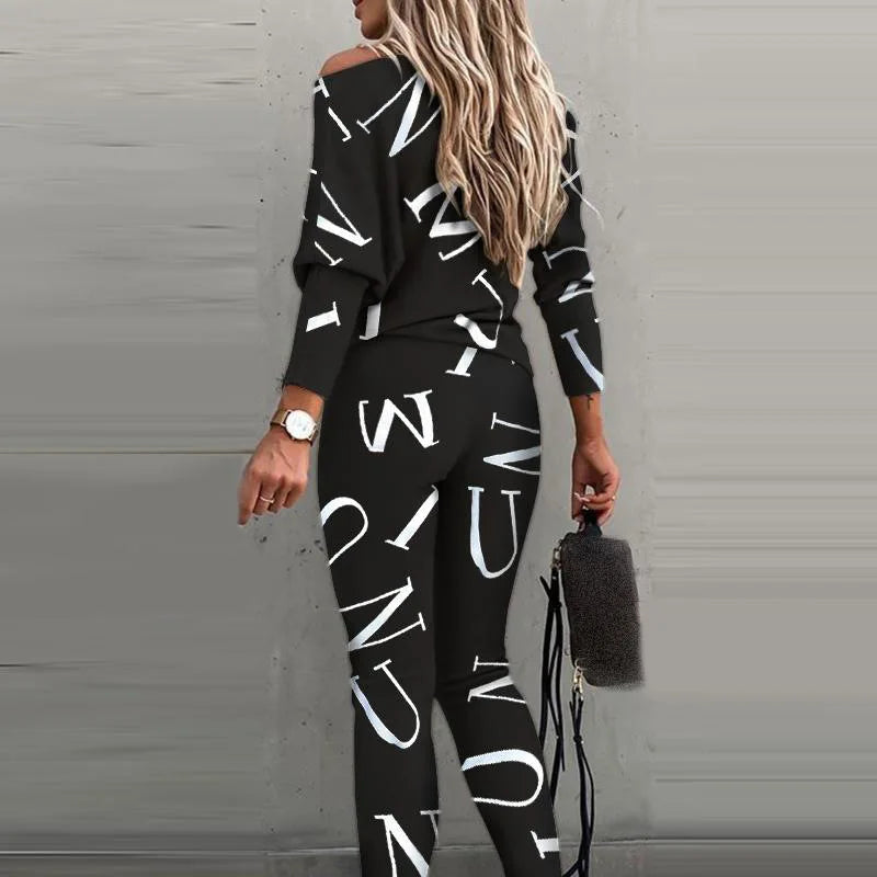 Back view of a woman wearing a black long sleeve top and pants tracksuit with white letter print