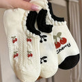 Three pairs of white ankle socks with cherry patterns and black frilled cuffs