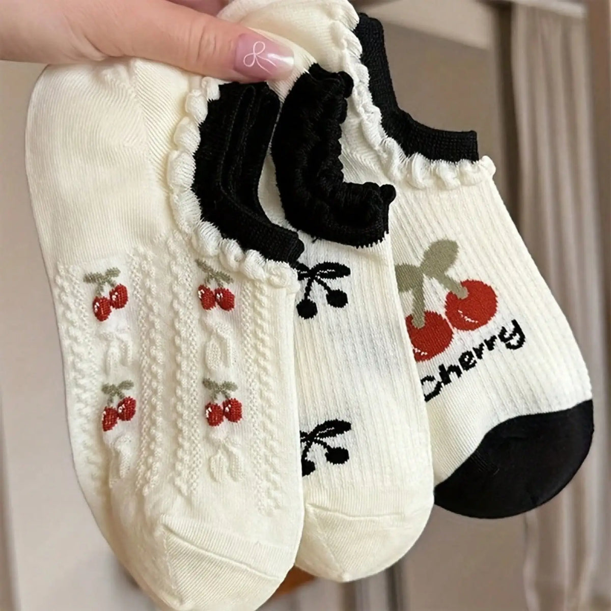 Three pairs of white ankle socks with cherry patterns and black frilled cuffs