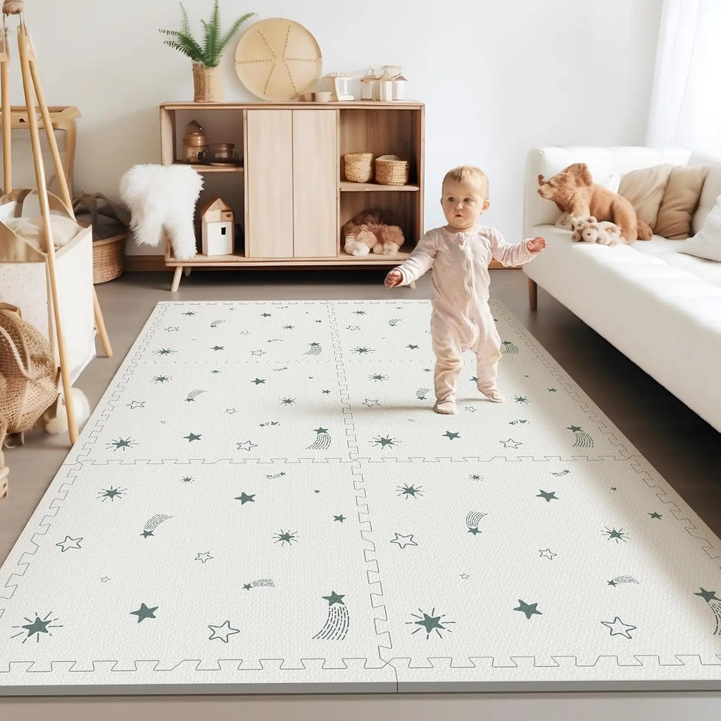 White baby play mat with green stars and shooting star patterns in a nursery setting with a baby.