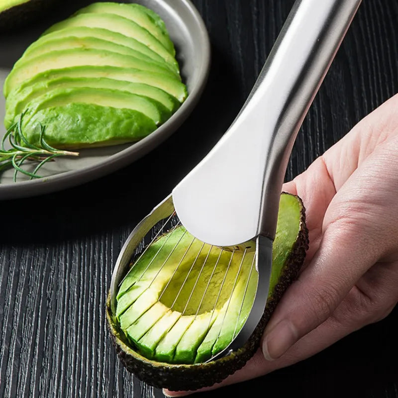 Stainless steel avocado slicer tool cutting a ripe avocado fruit