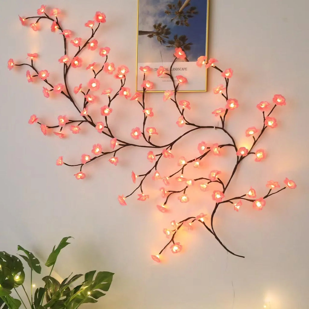Pink cherry blossom vine string lights wall decor next to framed picture and houseplant
