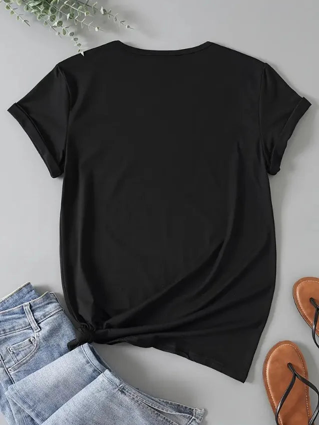 Black t-shirt laid flat next to jeans and sandals.