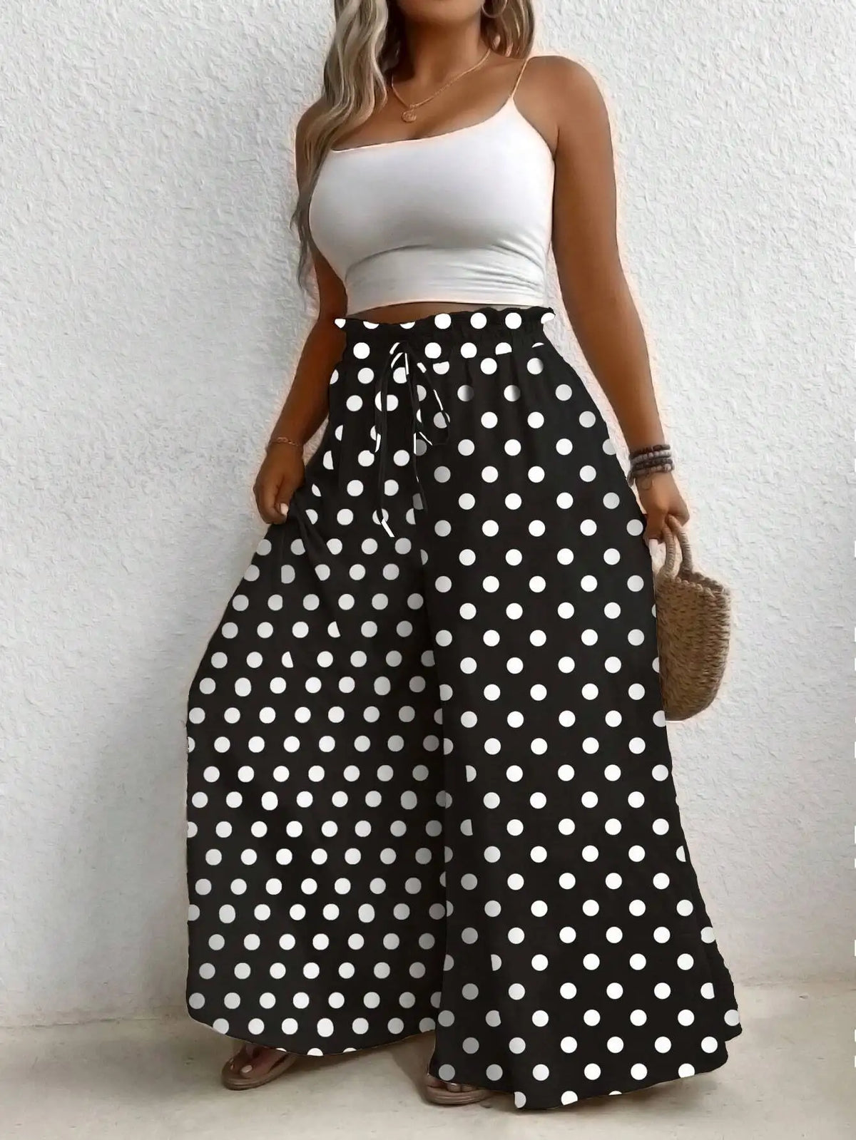 High waisted polka dot print wide leg pants with an elastic drawstring waist in black and white.