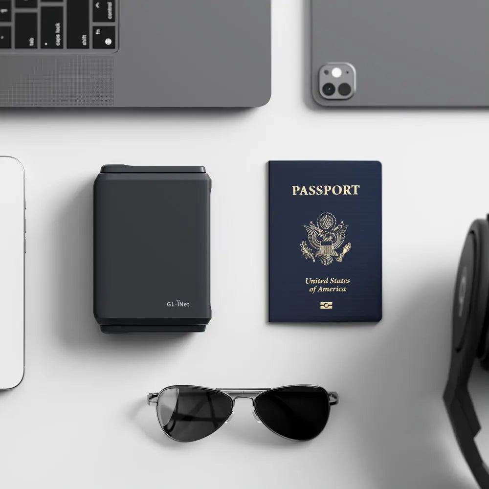 Top down travel router on a desk with a passport, sunglasses, and electronic devices