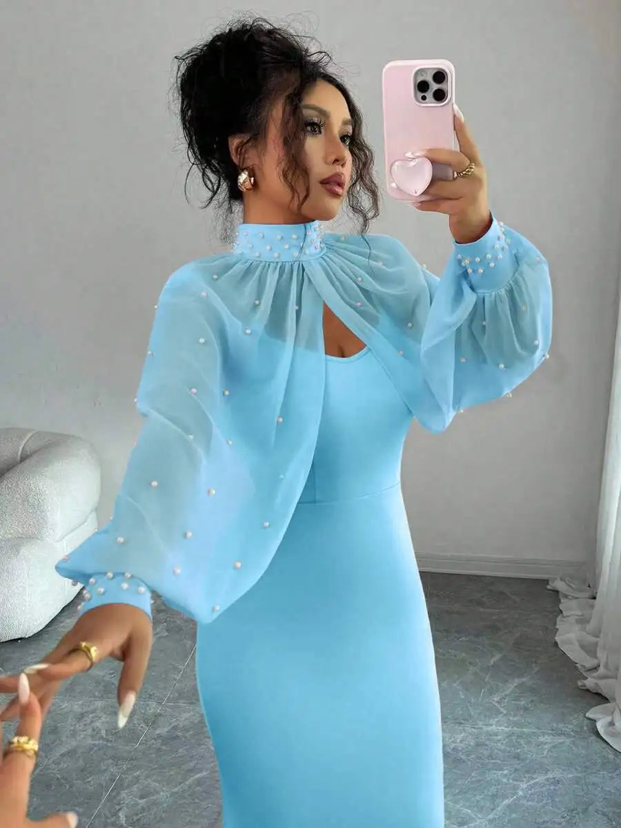 A woman wearing a light blue formal mermaid gown featuring a high neck and pearl-accented sheer sleeves.