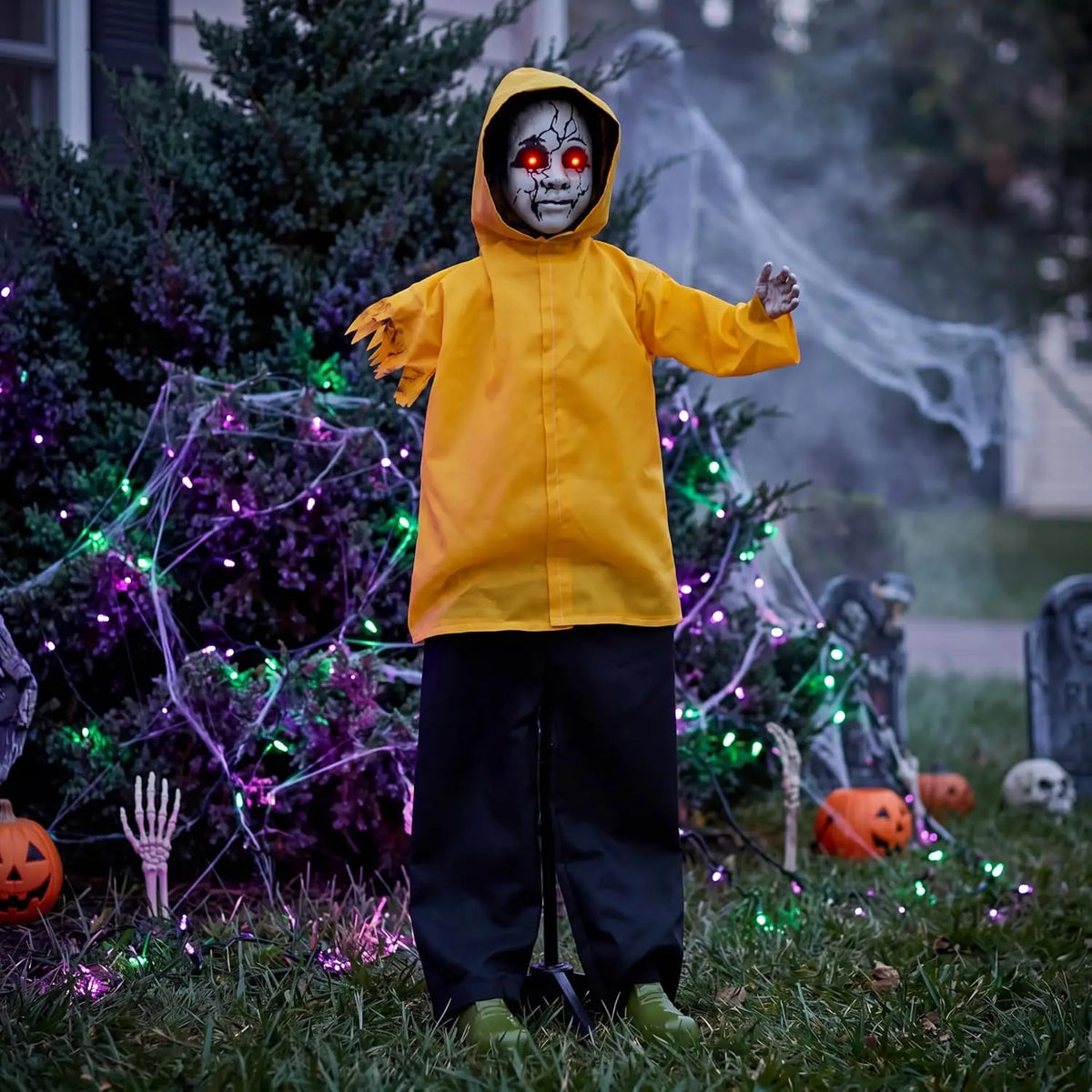 Life-sized Halloween ghost animatronic in a yellow raincoat with red glowing eyes in a yard
