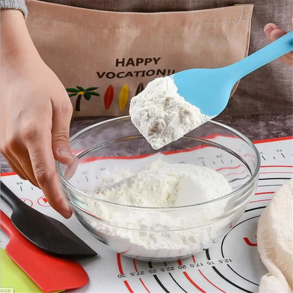 A person using a blue silicone spatula to mix ingredients in a glass bowl.