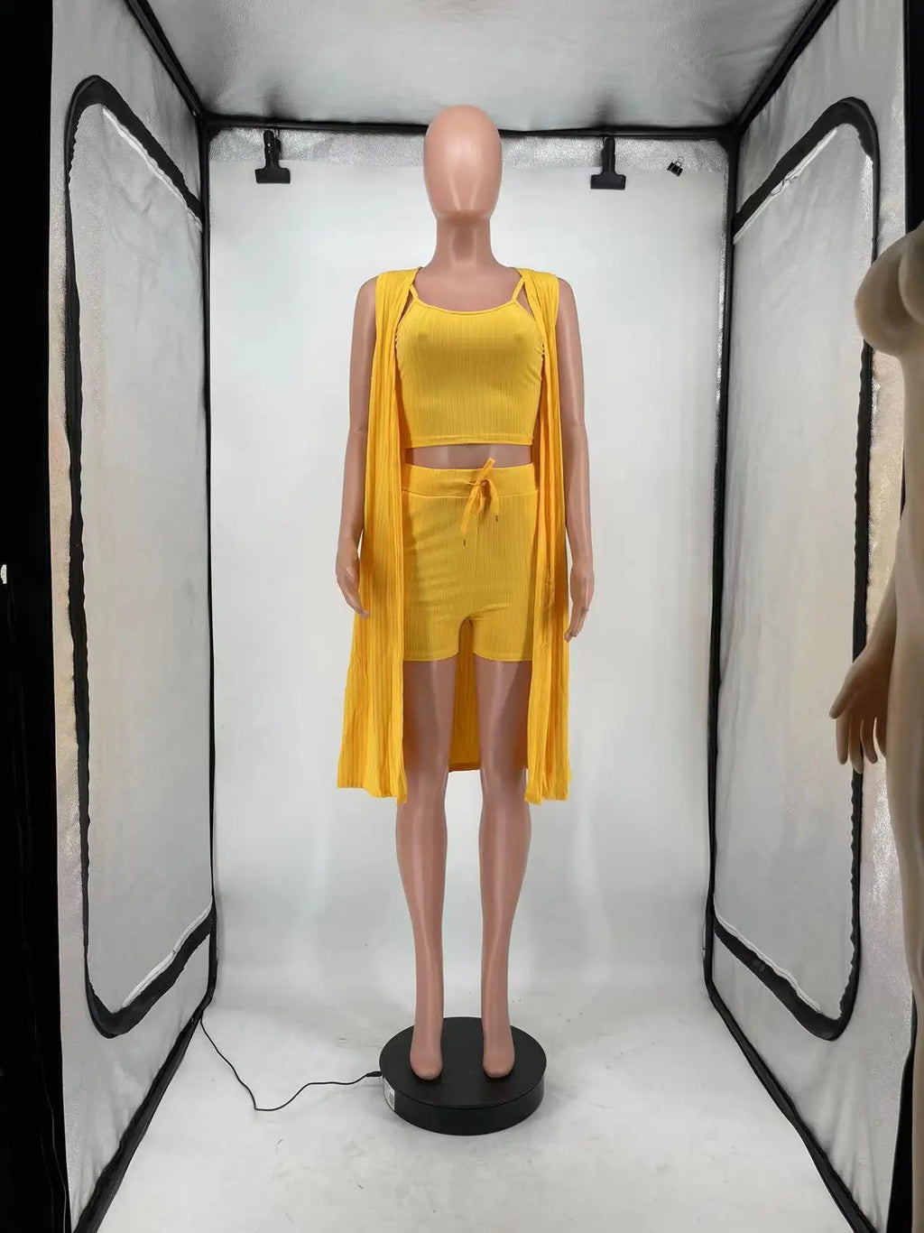 A yellow three-piece set of a ribbed tank top, drawstring shorts, and a long sleeveless cardigan displayed on a mannequin.