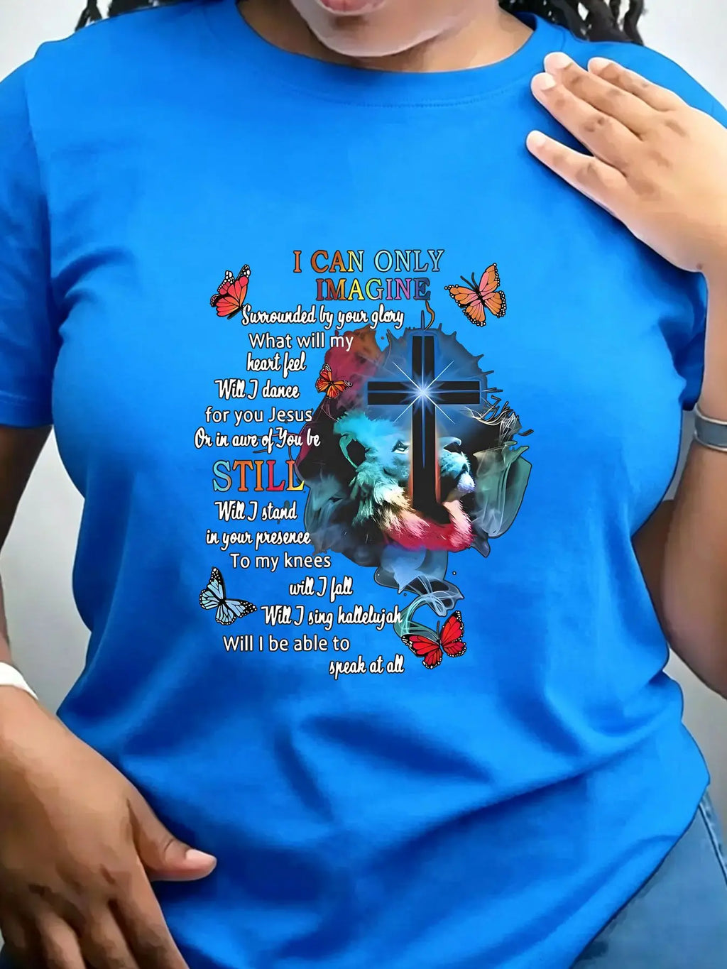 A royal blue short-sleeved crew neck t-shirt with a religious graphic print featuring a cross, lion, butterflies, and lyrics
