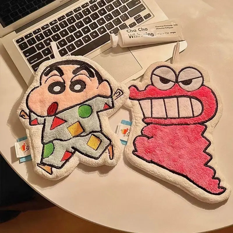 Two cartoon-themed hanging hand towels shaped like a boy and a creature resting on a laptop keyboard.