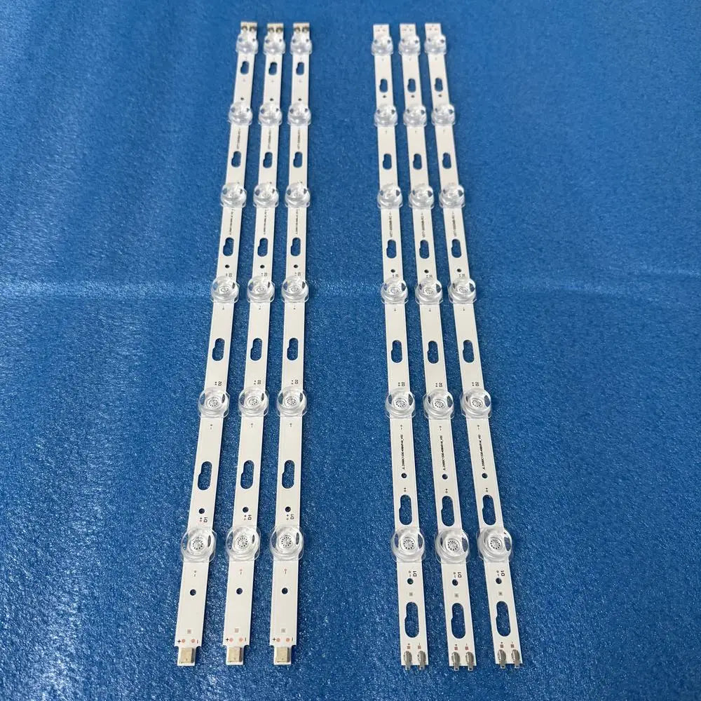 A set of six white LED backlight strips for television repair laid out on a blue surface.