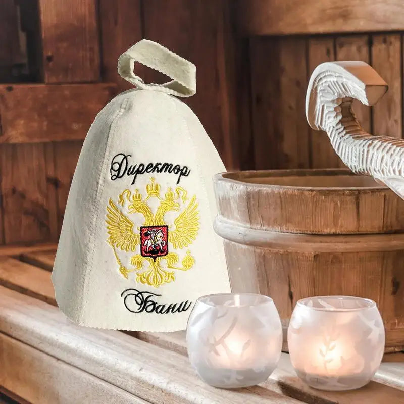 White felt sauna hat with Russian coat of arms embroidery in a sauna setting with wooden accessories.