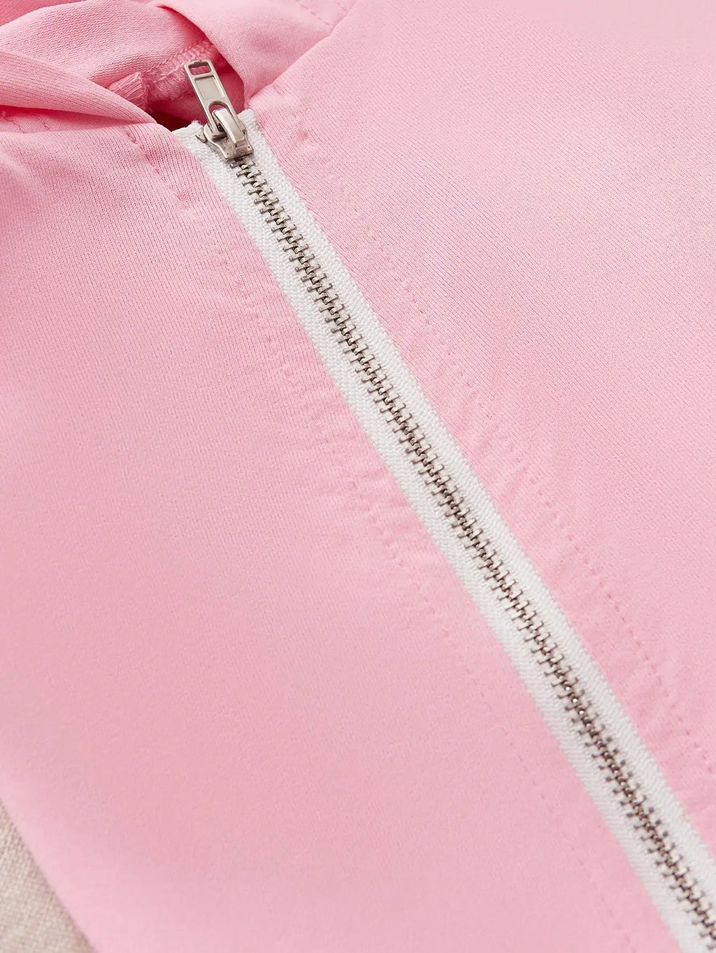 Close-up of the zipper detail on a pink hooded sweatshirt.