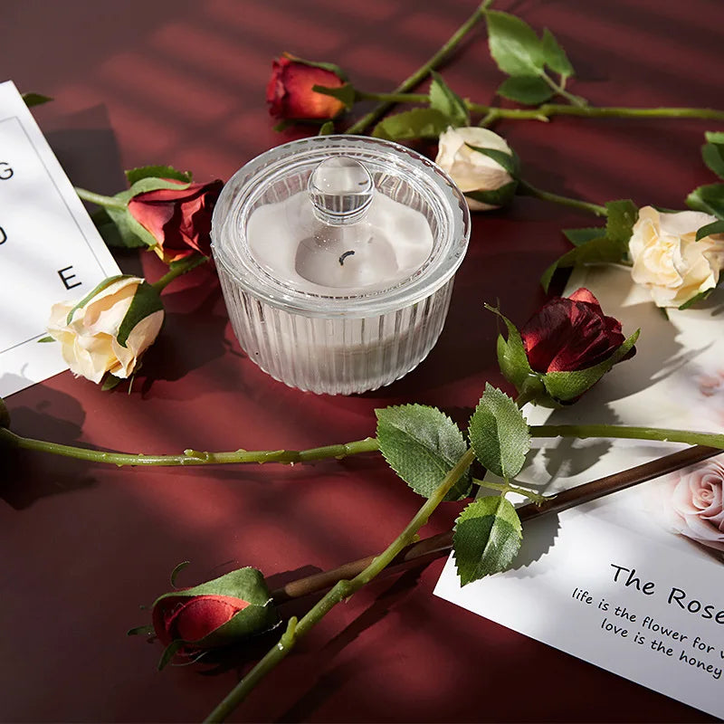 Decorative still life with a candle and roses on a dark red photography backdrop