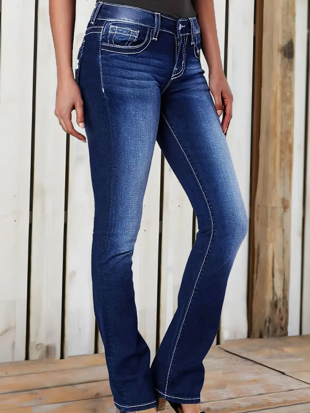 Side view of women's deep blue flared jeans with white contrast stitching