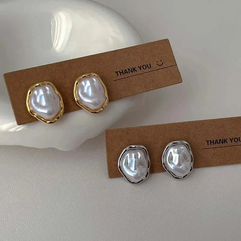 Irregular round pearl earrings with gold and silver metal rims on cardboard display cards