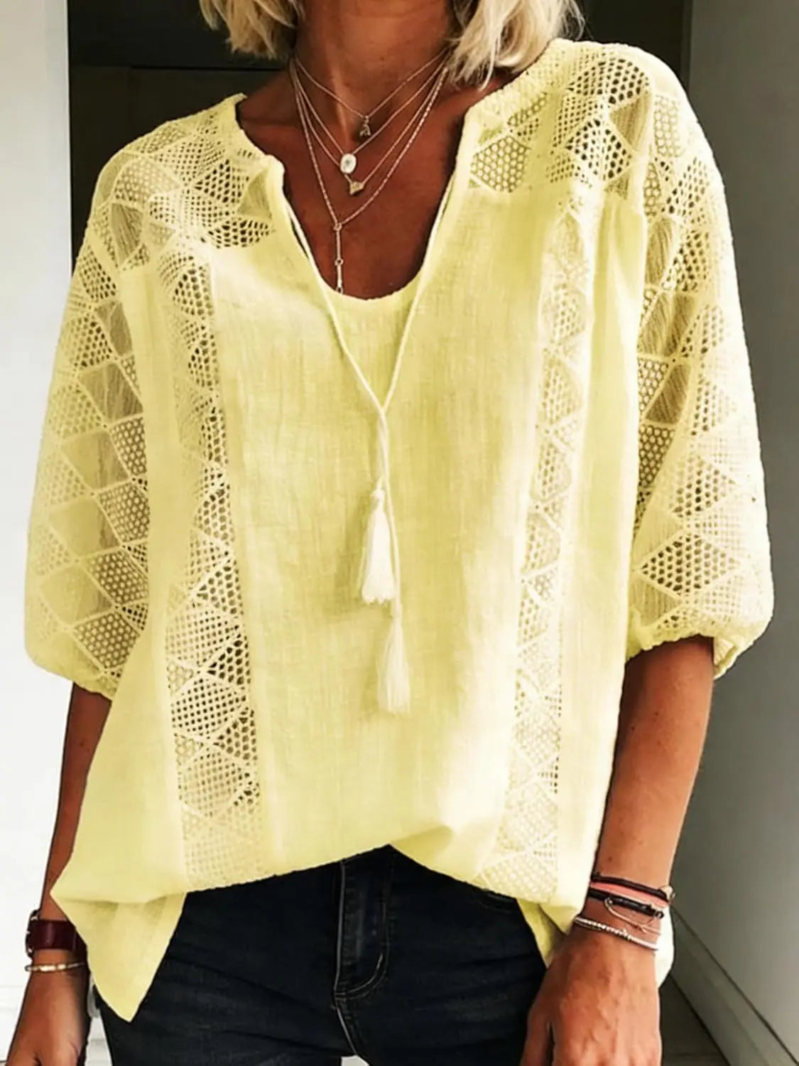 Women's yellow loose-fit blouse with lace inserts, tassel tie neck, and 3/4 sleeves