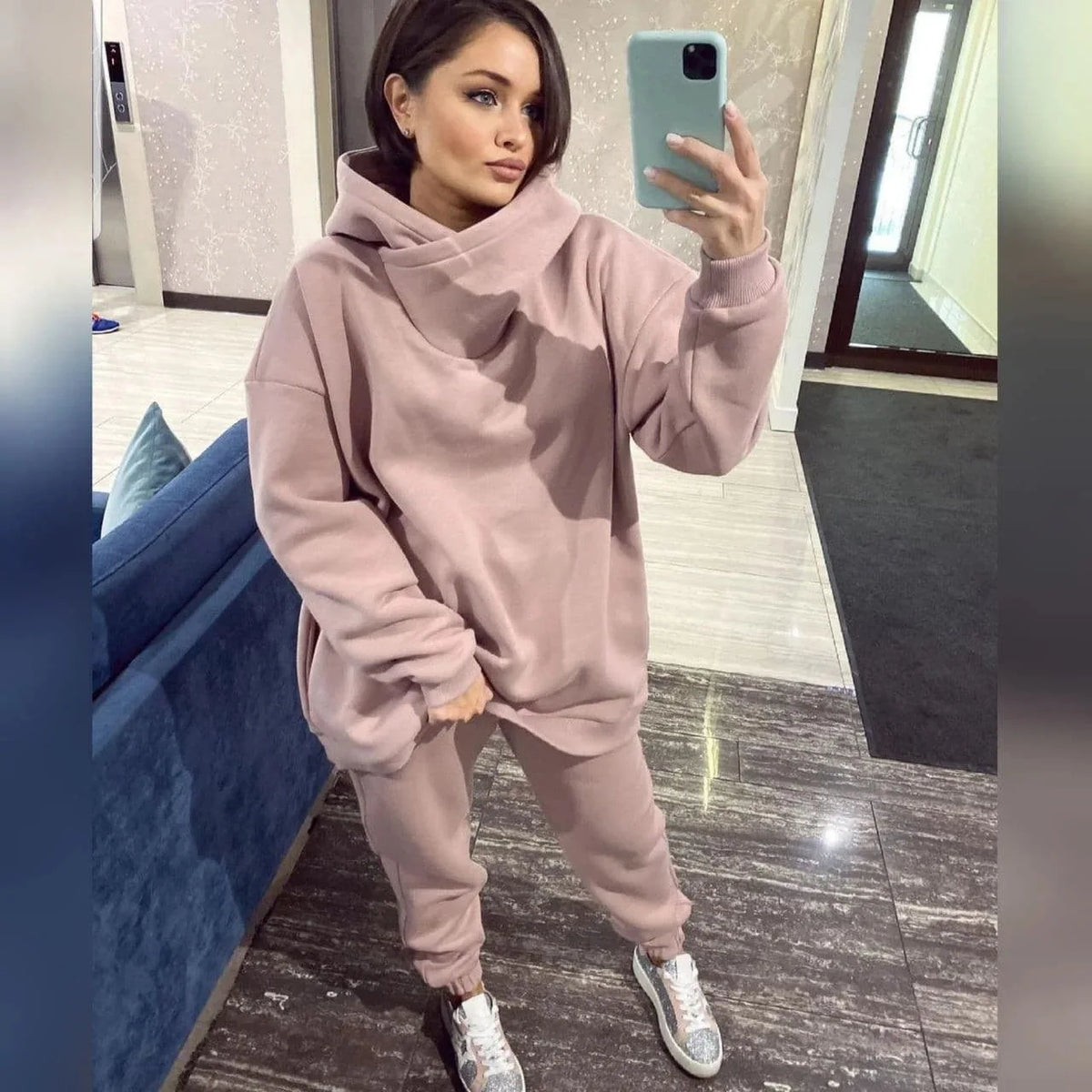 A pink two-piece tracksuit with an oversized hooded sweatshirt and sweatpants