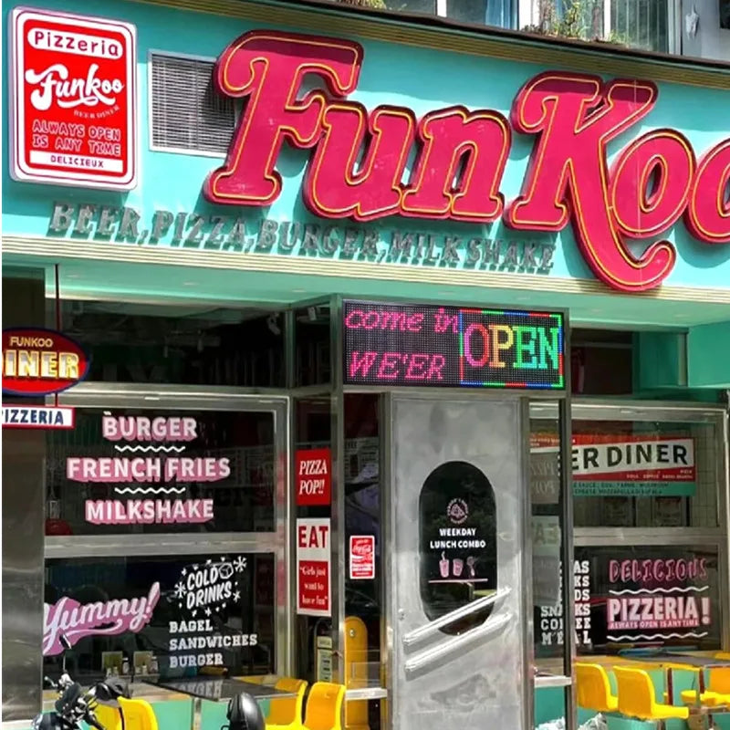 A modern pizza diner storefront with a programmable LED sign displayed in the window.