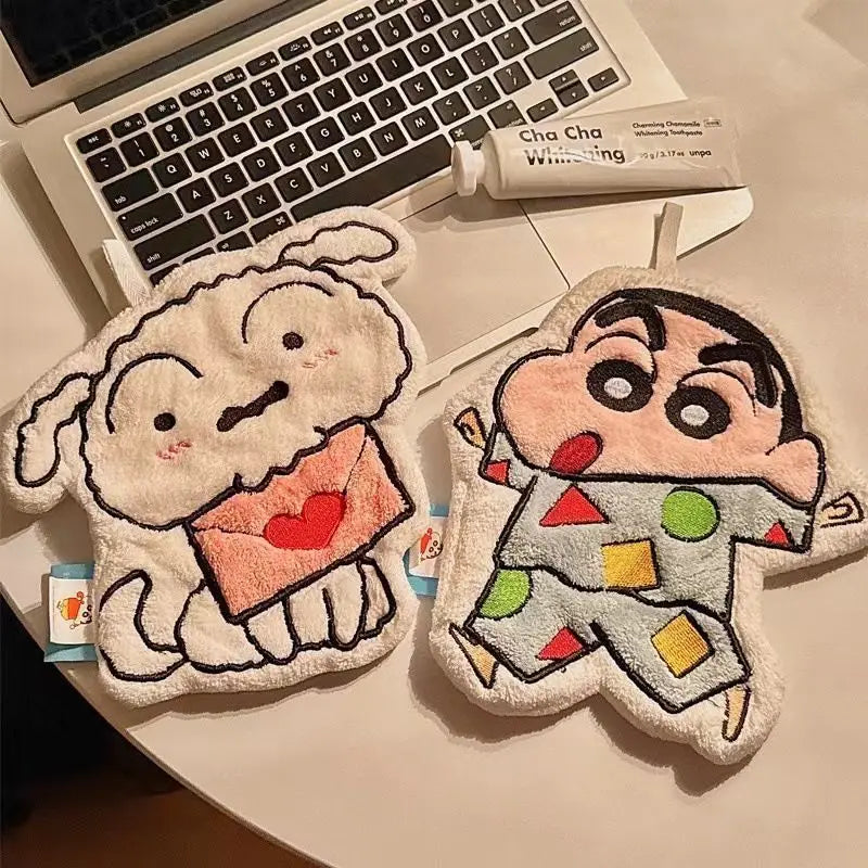Two cartoon-themed hanging hand towels shaped like a dog and a boy resting on a laptop keyboard.