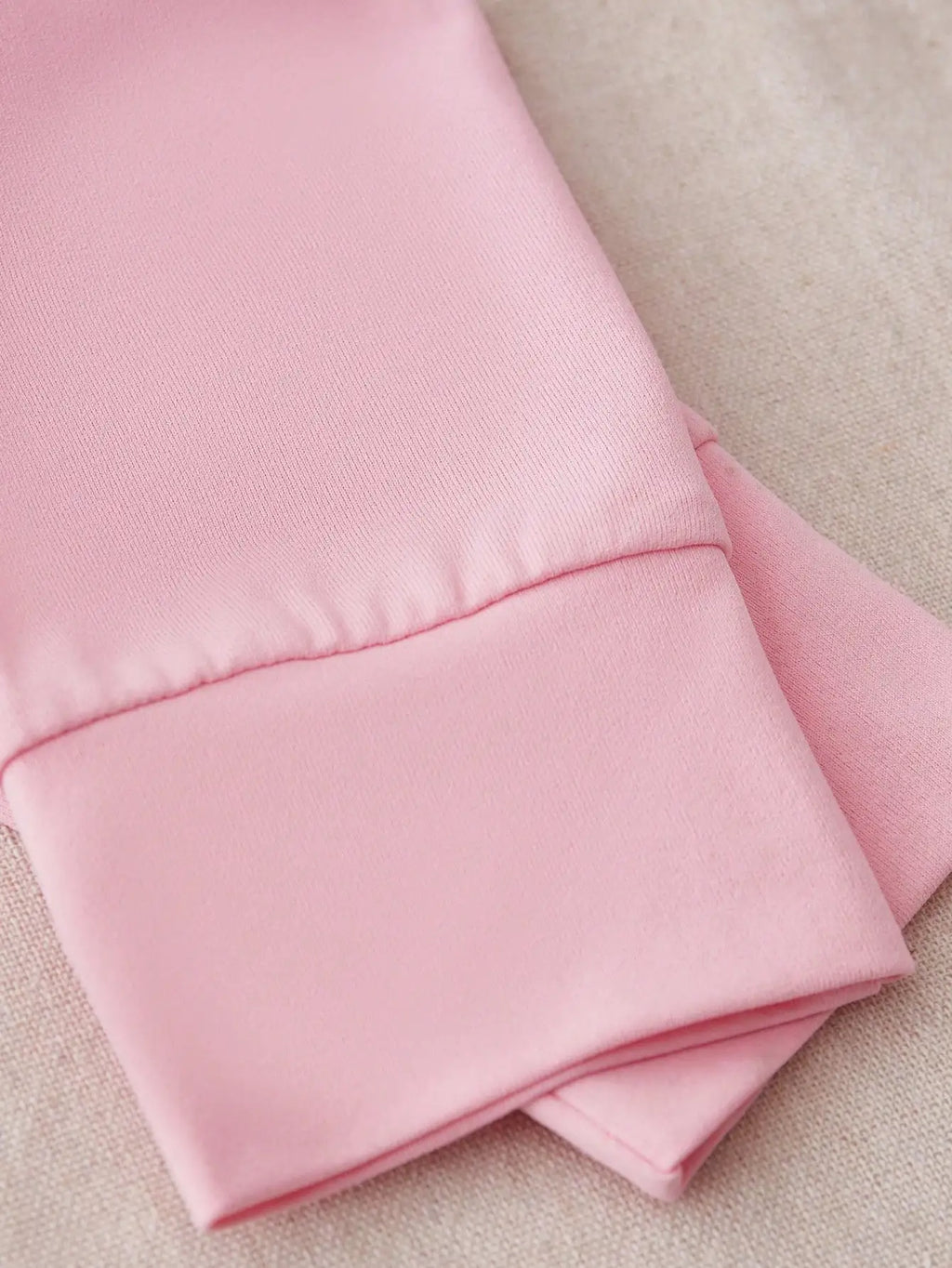 Close-up of the cuffed sleeve on a pink long-sleeved garment.