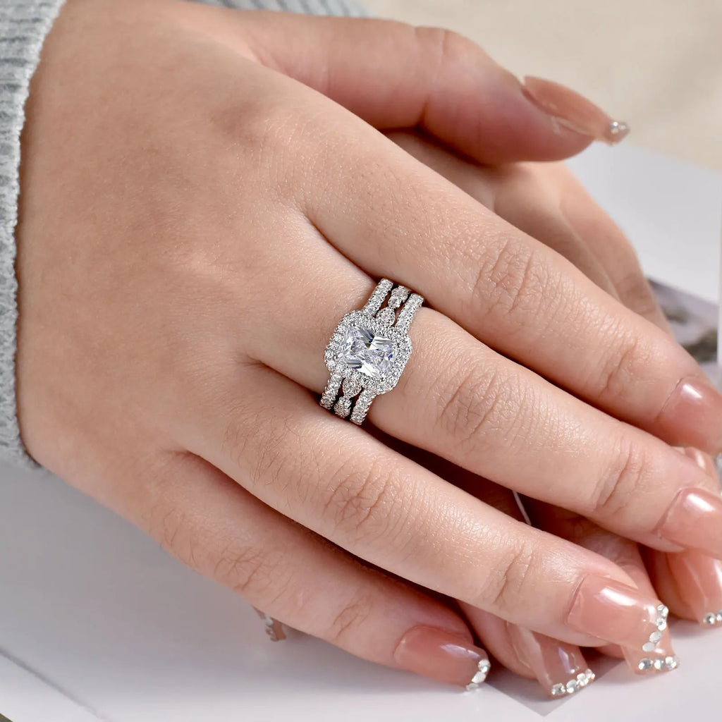 Hand wearing sterling silver engagement ring set with rectangular stone and pave bands