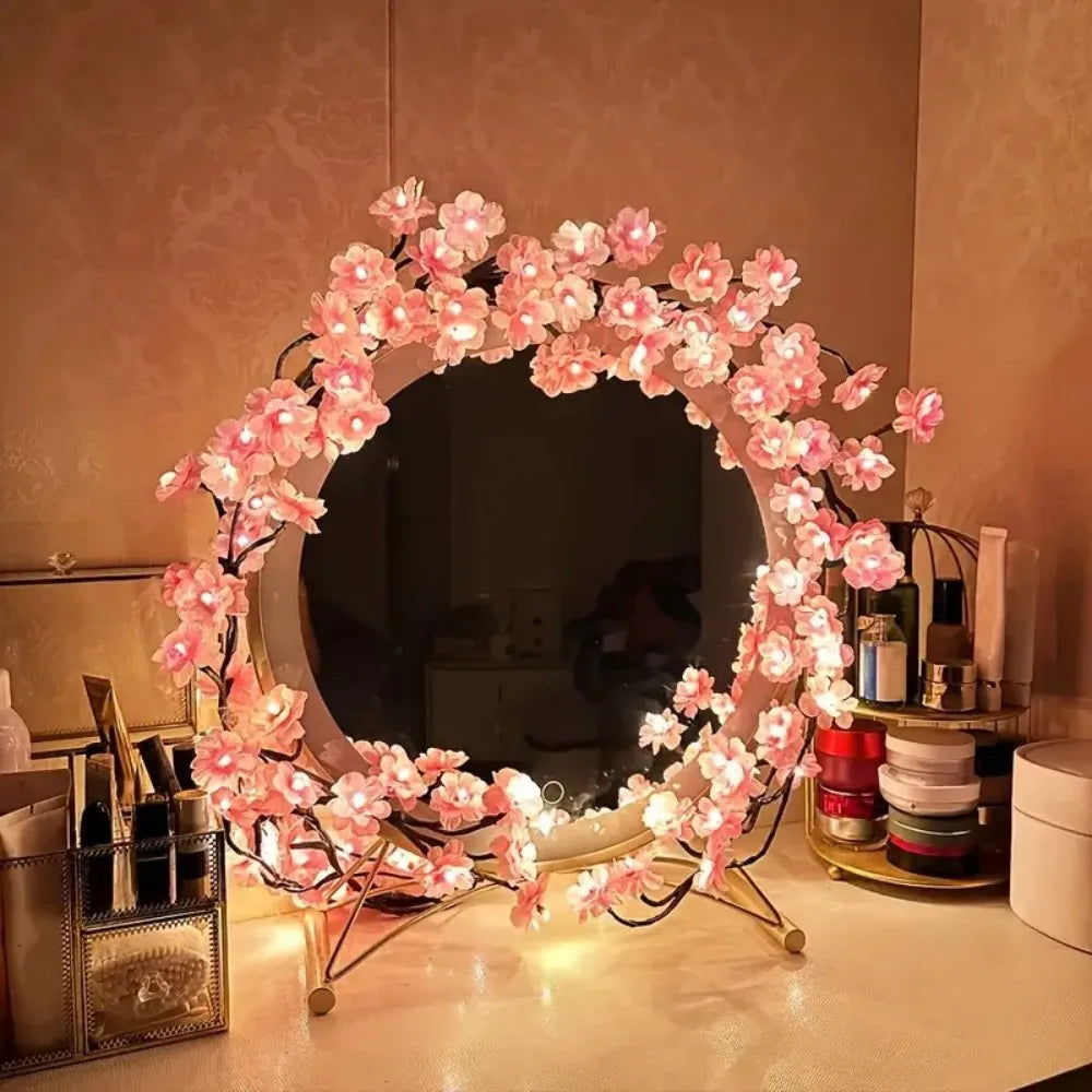 Round vanity mirror decorated with illuminated artificial cherry blossom vine lights