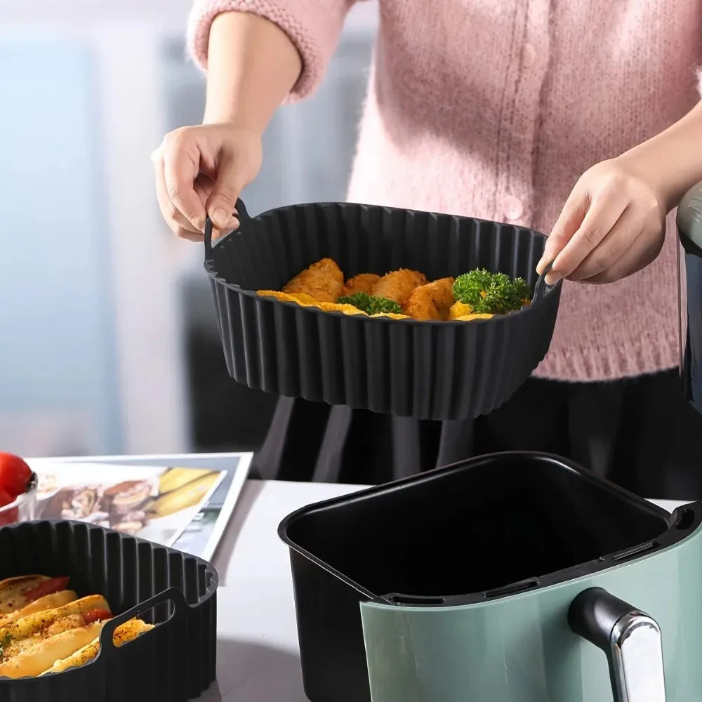 Hands holding a black silicone air fryer basket liner