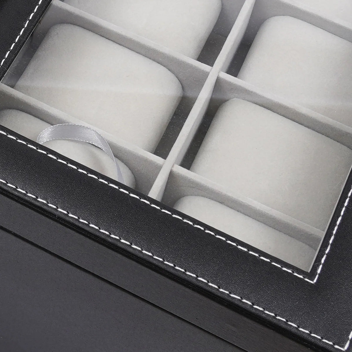 Close up view of the glass lid on a black leather watch display case.