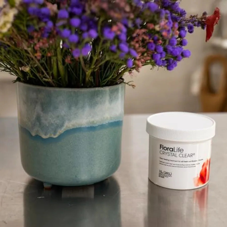 Container of flower food powder next to a blue vase with flowers