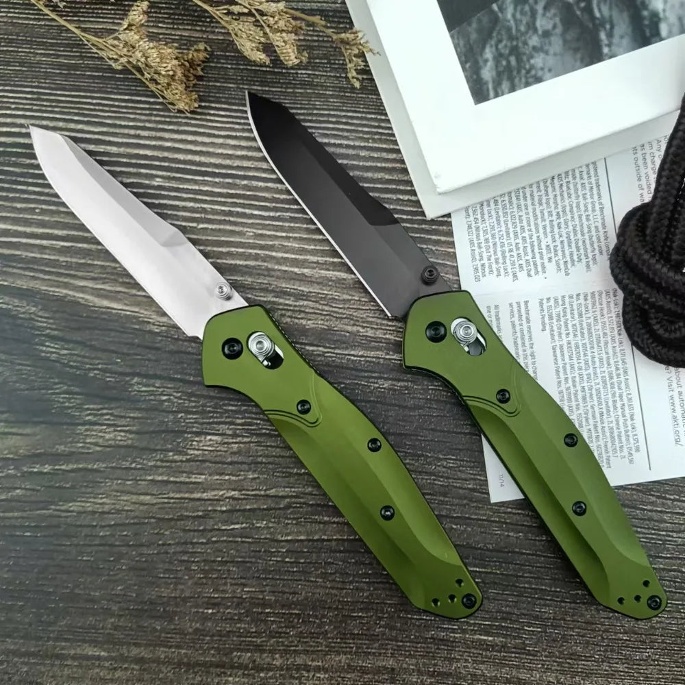 Two olive green folding knives with silver and black blades on a wooden surface.