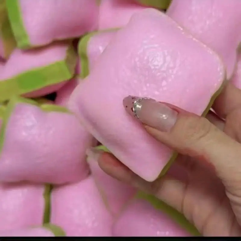 A hand holding a pink squishy toy shaped like a slice of toast