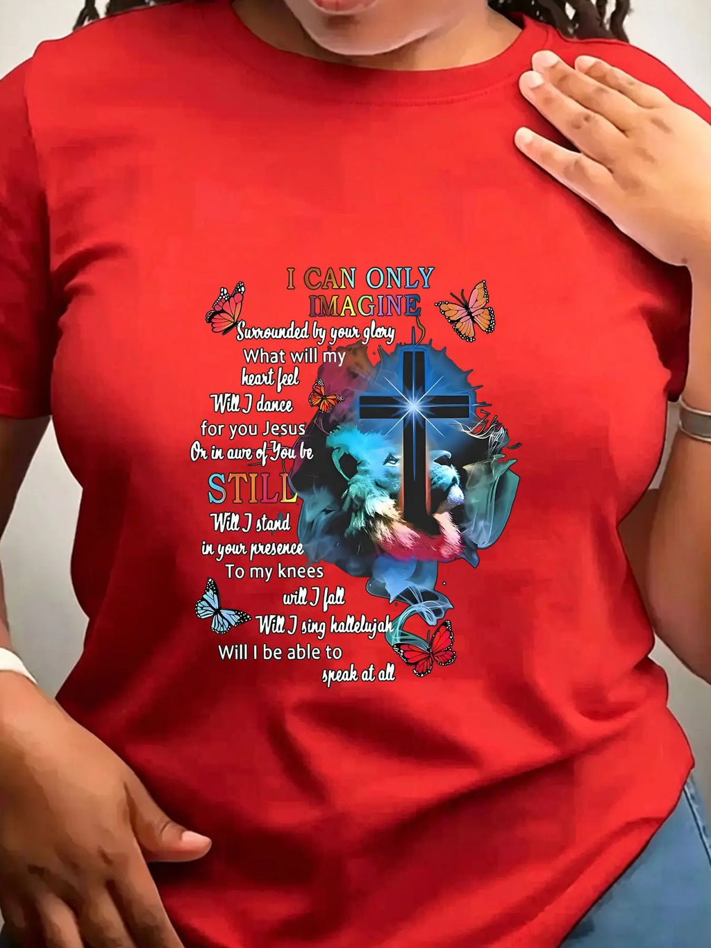 A red short-sleeved crew neck t-shirt with a religious graphic print featuring a cross, lion, butterflies, and lyrics