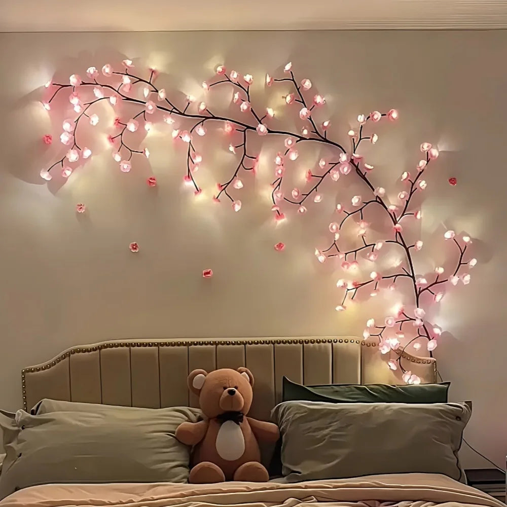 Cherry blossom LED string light vine wall decor with pink flower lights above a bed