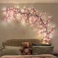 Cherry blossom LED string light vine wall decor with pink flower lights above a bed